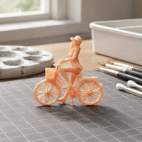Peach Plastic Girl Bike Figurine Spoked Wheels Girl on Cycle Figure